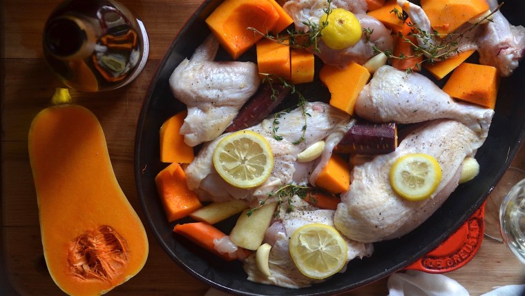 Chicken in roasting pan with butternut squash and lemons.