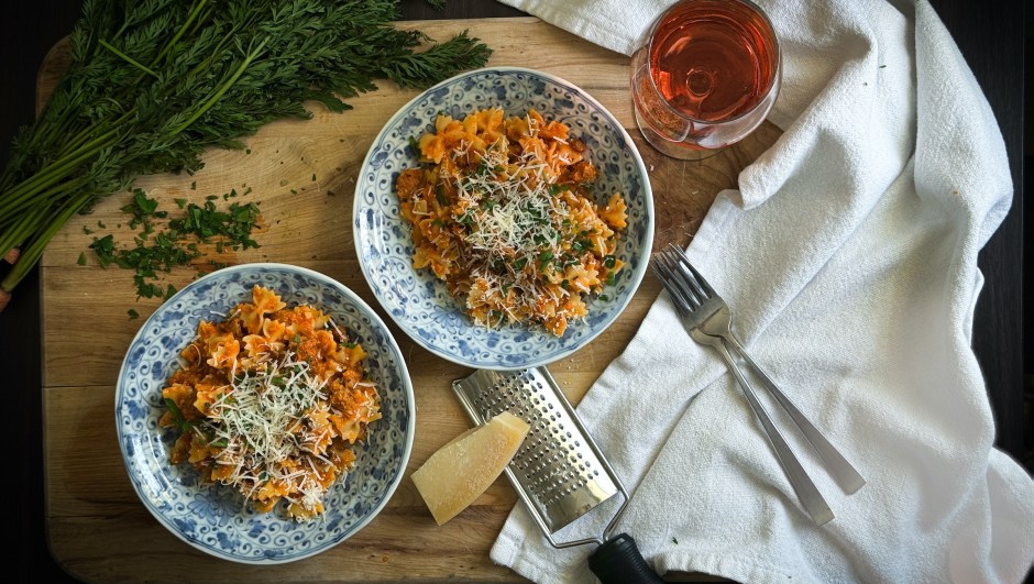 Two bowls of farfalle pasta with carrot sauce and cheese